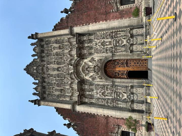 Elaborate stone carvings framing the massive wooden doors of an ornate baroque church in Mexico