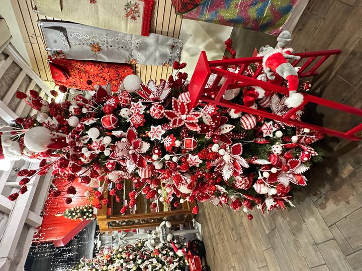Lavish red-and-white decorated Christmas tree inside a craft store with matching red stool