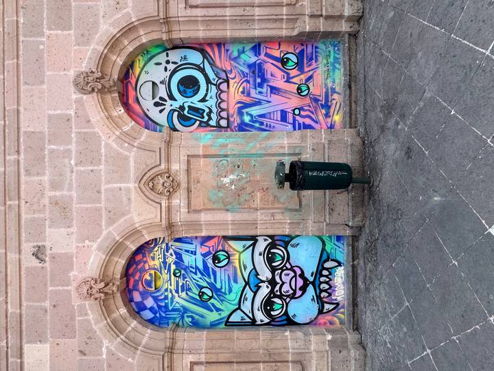Colorful street art of cartoon monsters painted on two arched doorways in a stone wall