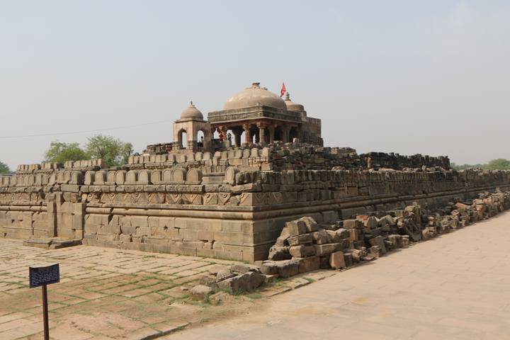 Ancient stone temple ruins with weathered carvings set against a pale sky.