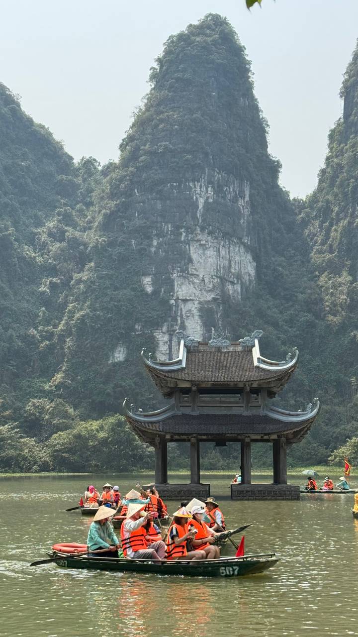 Stone pagoda set against towering limestone cliffs and dense greenery in Ninh Binh province.