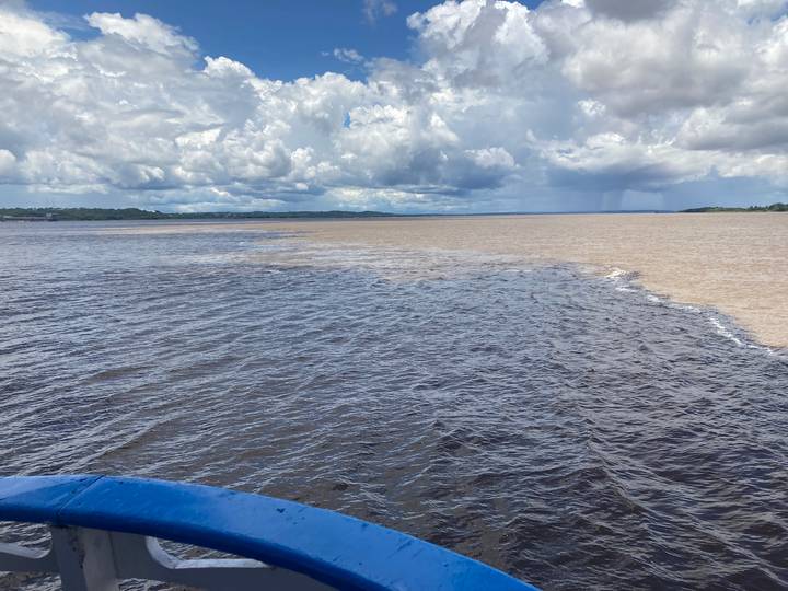 Confluence of two differently colored rivers under dramatic cloudy sky