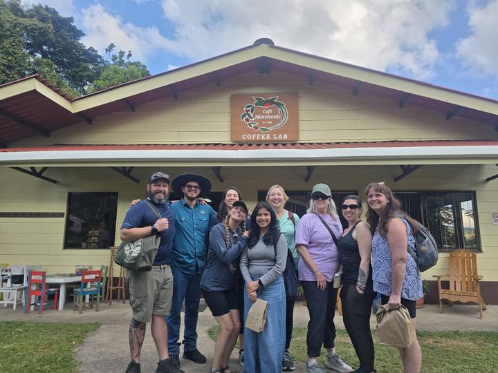 Tourists gathered in front of a coffee lab building smiling for camera