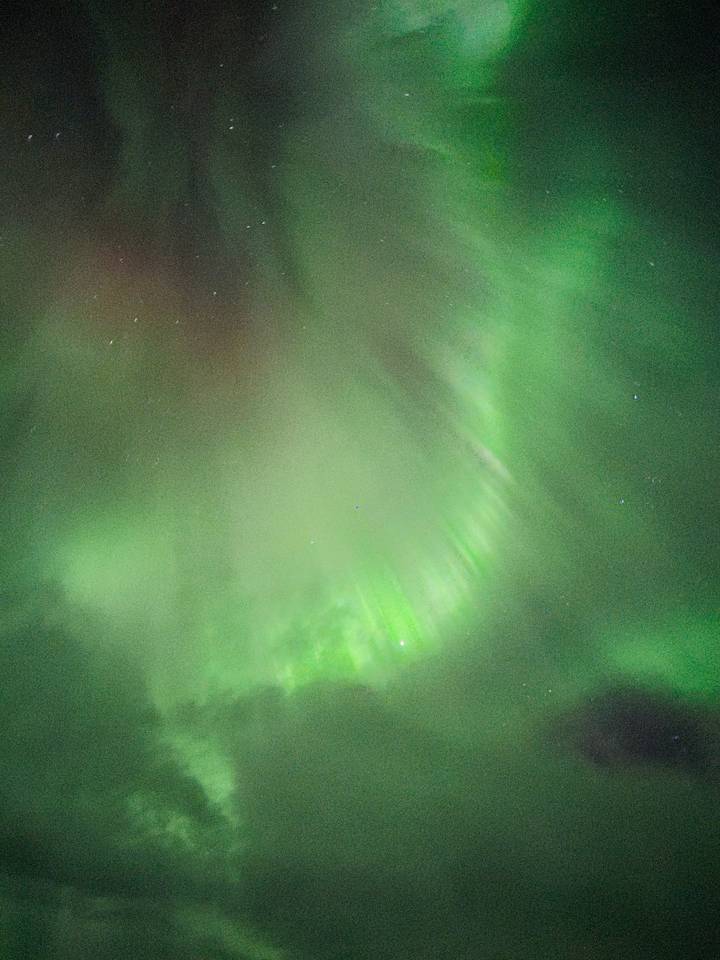 Green aurora borealis curtains swirling across a starry winter night sky