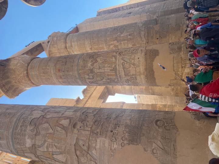 Crowds admire towering hieroglyph-covered columns inside Karnak Temple complex.