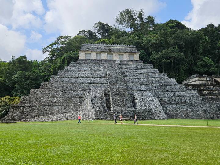 View of the Temple of the Inscriptions pyramid at Palenque with visitors on the lawn.