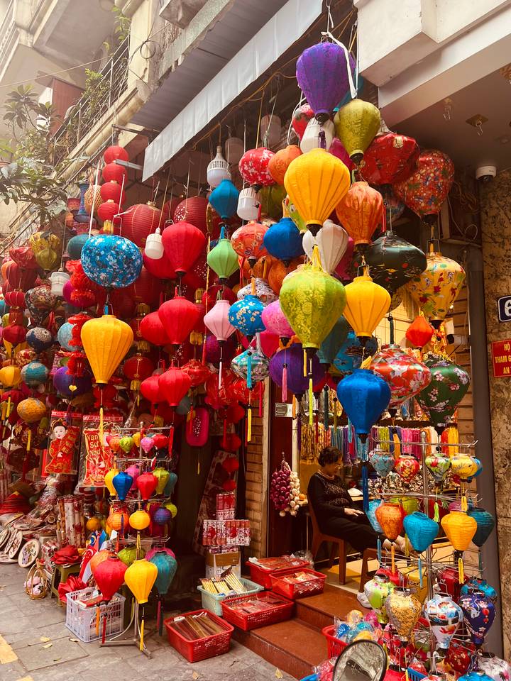 Vibrant display of multi-colored paper lanterns hanging in a market stall.