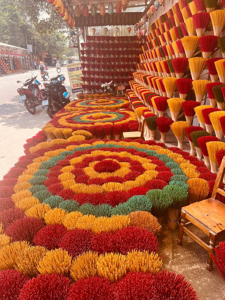 Brightly colored incense sticks arranged in circular patterns drying in the sun.