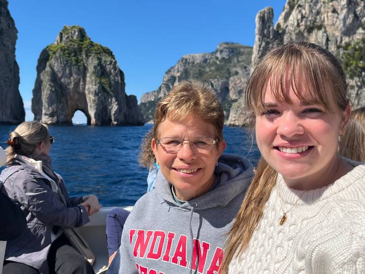 Family enjoying a boat ride with the famous Capri Faraglioni rock arch in the background