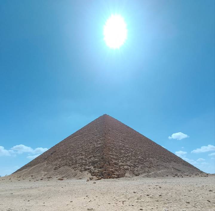 Triangular profile of the Great Pyramid of Giza rising toward a bright noon sun