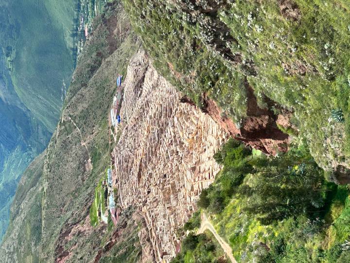 Aerial view of terraced salt pans cascading down a steep Andean valley at Maras.