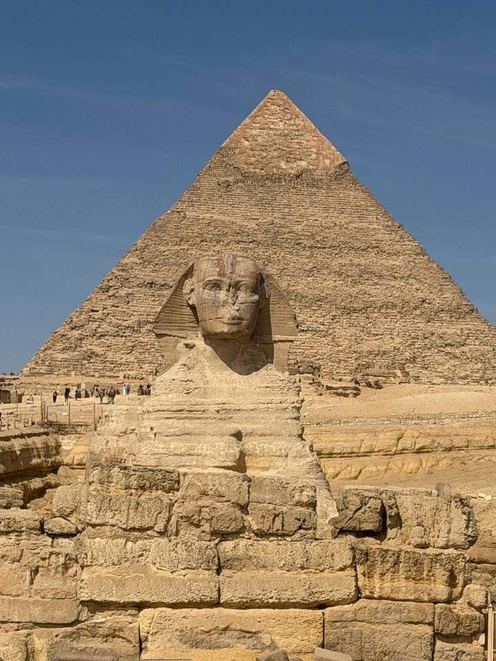 Iconic Great Sphinx in front of the Pyramid of Khafre under a clear blue Egyptian sky.