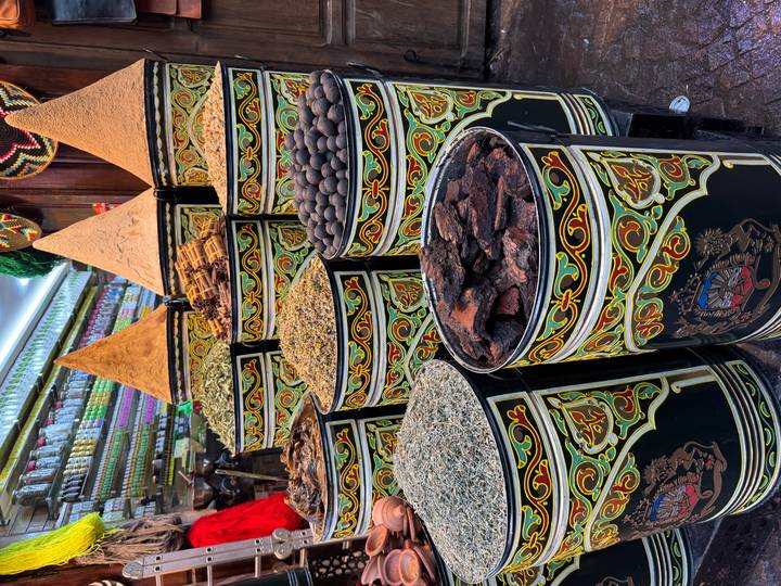 Colorful cylindrical spice barrels piled high in a Moroccan market stall