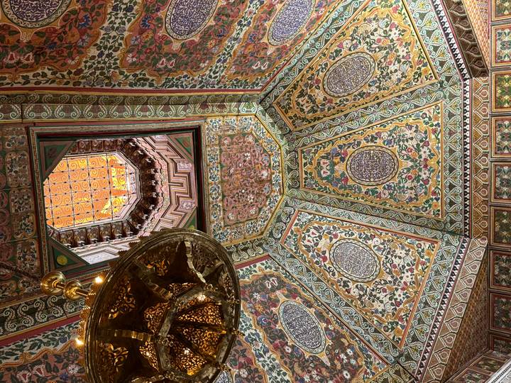 Opulent painted ceiling and ornate lantern inside a historic Moroccan palace