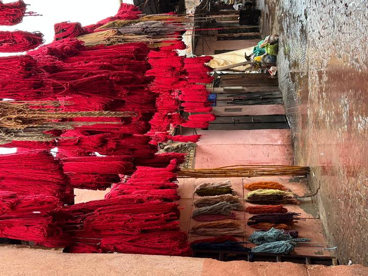 Bundles of bright red dyed wool hanging to dry in a narrow Marrakech alleyway