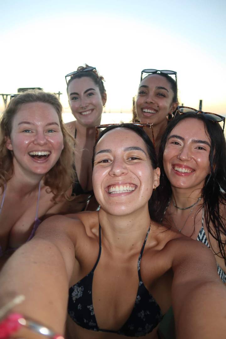 Selfie of five smiling young women, wet from swimming, enjoying a sunny day together.