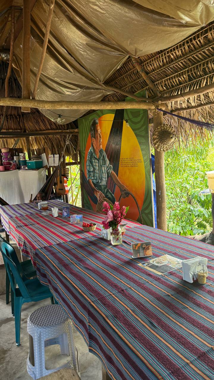 Colorful woven tablecloths, fresh flowers and artwork decorate an open-air rural dining area.