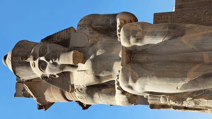 Stone statue of a seated pharaoh with blue sky backdrop showcasing fine ancient craftsmanship.