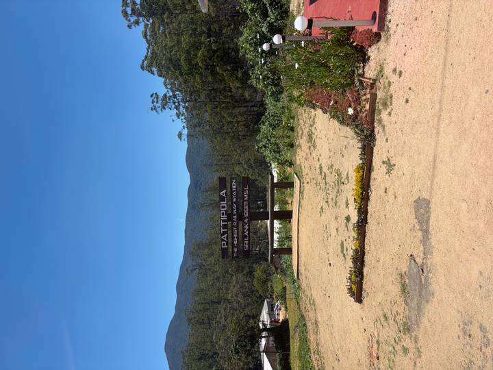 Mountain backdrop with a wooden sign reading 'Pattipola Highest Railway Station Sri Lanka 1898 MSL'.