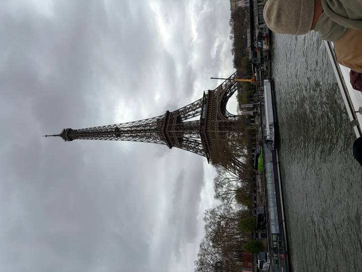 Eiffel Tower rising over the Seine River on an overcast day with boats moored along quay