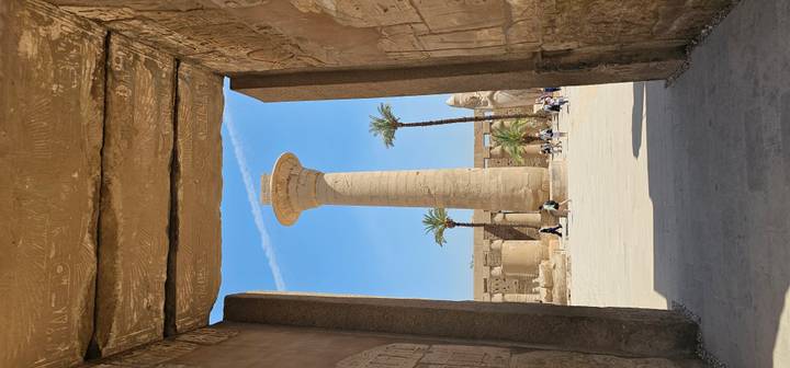Massive sandstone column framed by monumental doorway at sprawling temple site