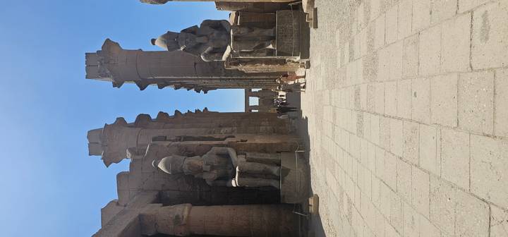 Grand avenue flanked by colossal seated pharaoh statues inside ancient temple complex