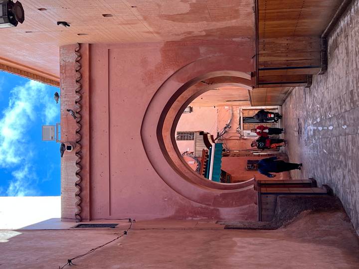 Narrow pink alleyway framed by horseshoe arch with pedestrians in historic medina
