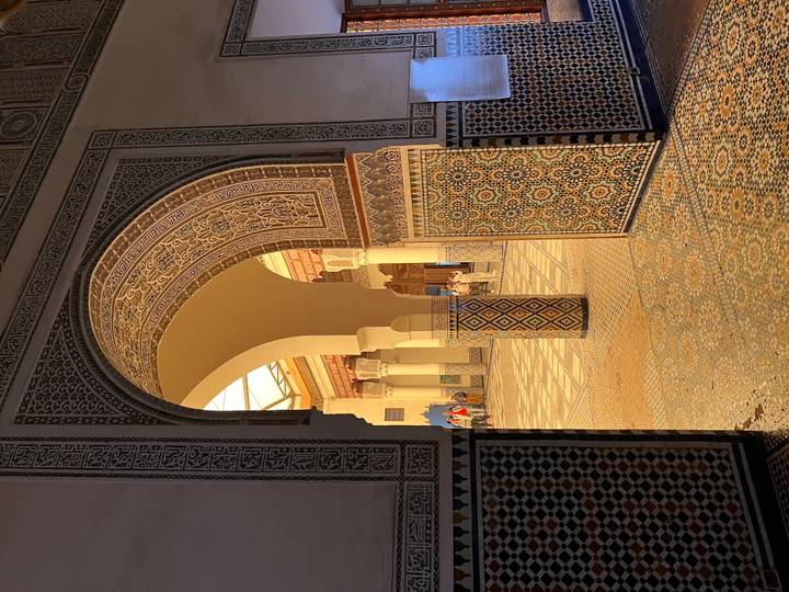 Intricately tiled archway opening to ornate courtyard bathed in warm light