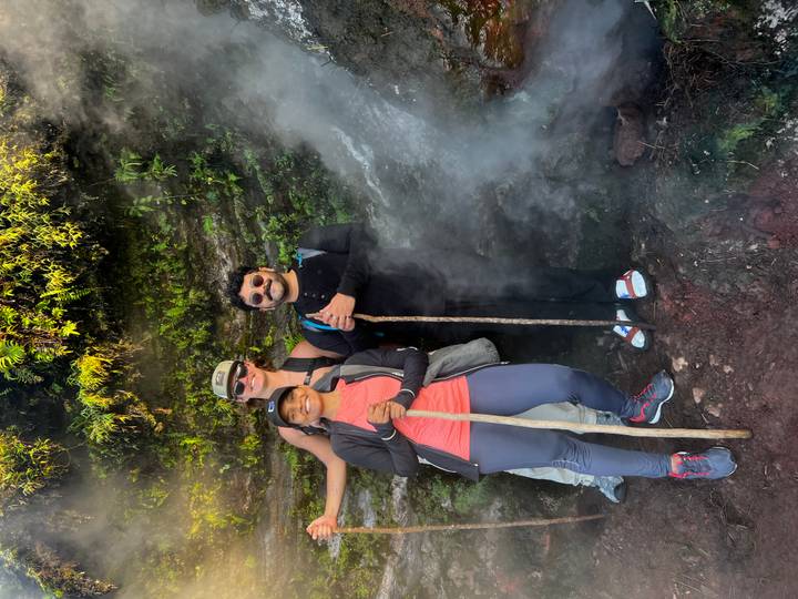 Small group stands beside steaming vent on the slopes of Mount Batur holding walking sticks.