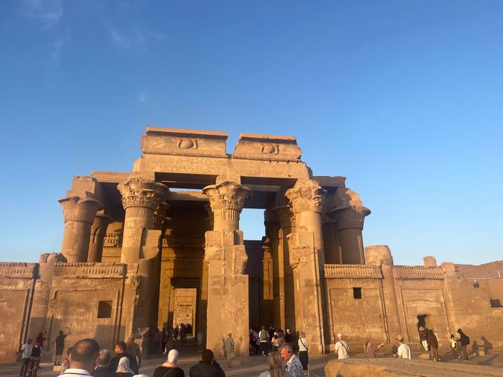 Kom Ombo Temple lit by warm evening light against a clear blue sky.