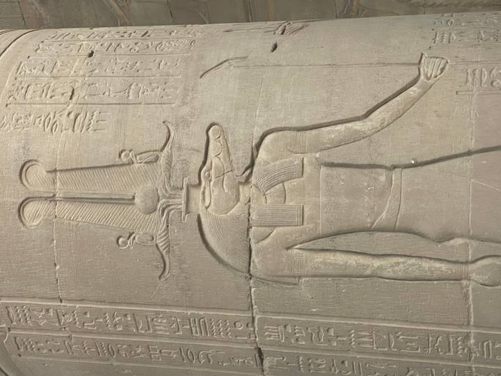 Relief carving of the crocodile-headed god Sobek with hieroglyphs on sandstone wall.