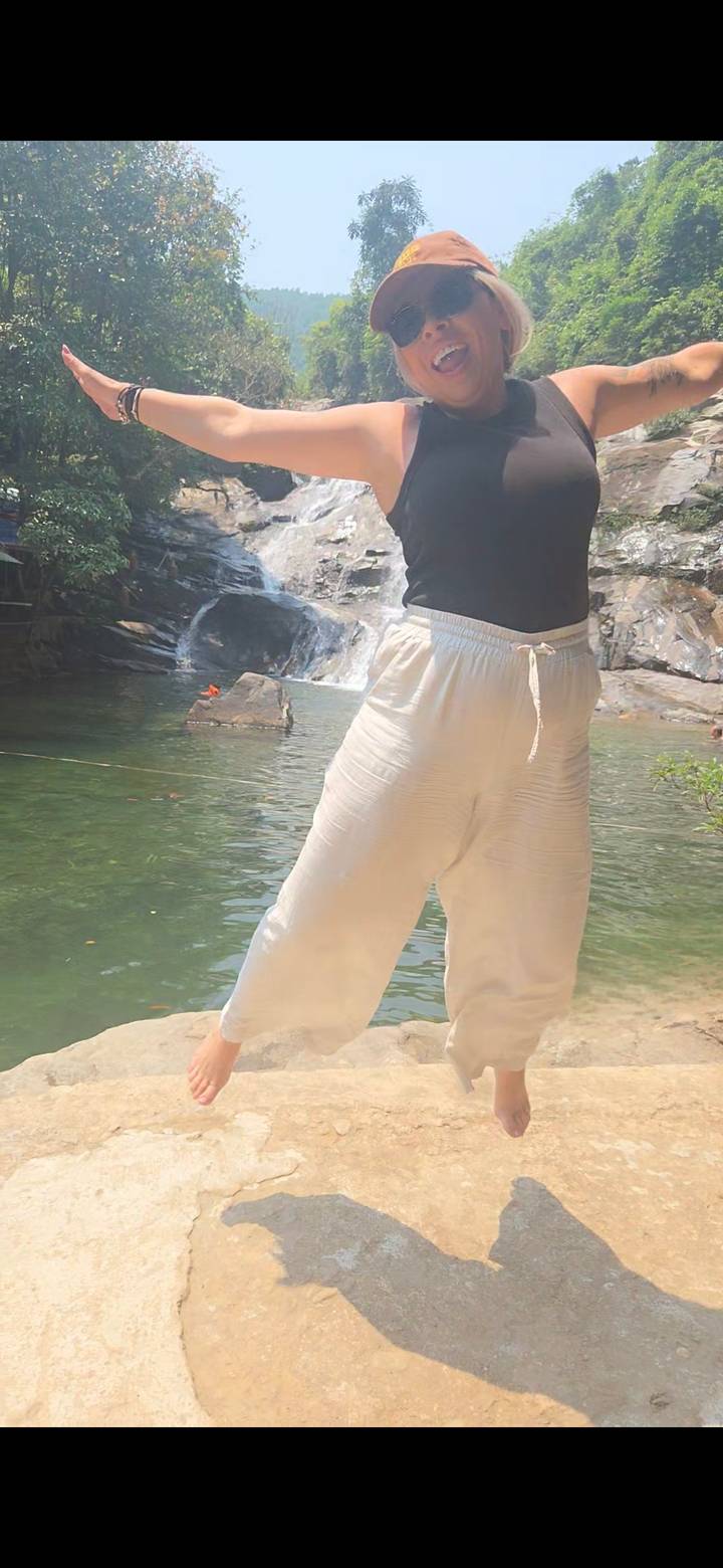 Partial view of a person standing at a riverside pool; composition is cropped and soft.
