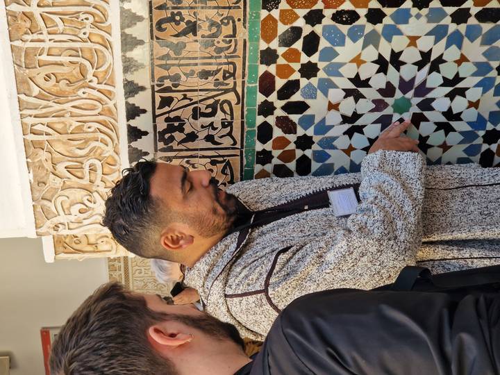 Local guide pointing out colorful zellige tile patterns and Arabic calligraphy