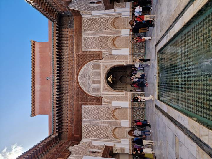 Ben Youssef Madrasa courtyard with reflecting pool and visitors admiring ornate entrance