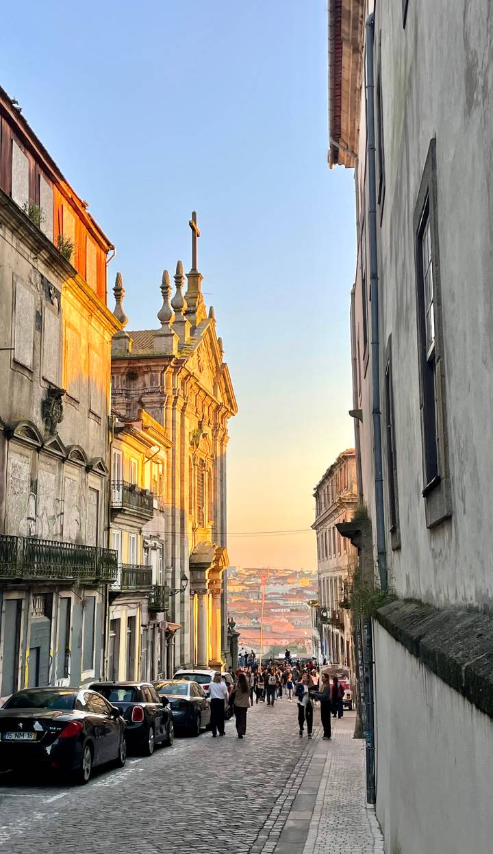 Golden-hour light illuminating an ornate historic church façade between narrow city buildings.