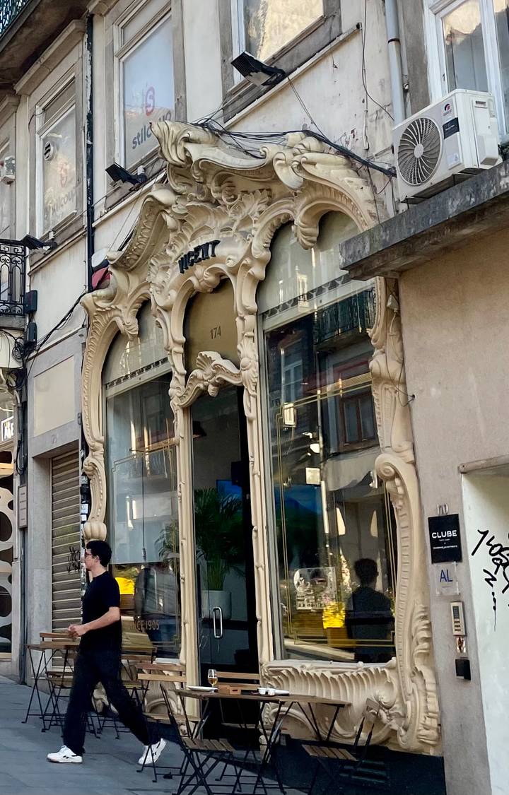Art Nouveau storefront with ornate stone carvings and large glass windows in Porto.