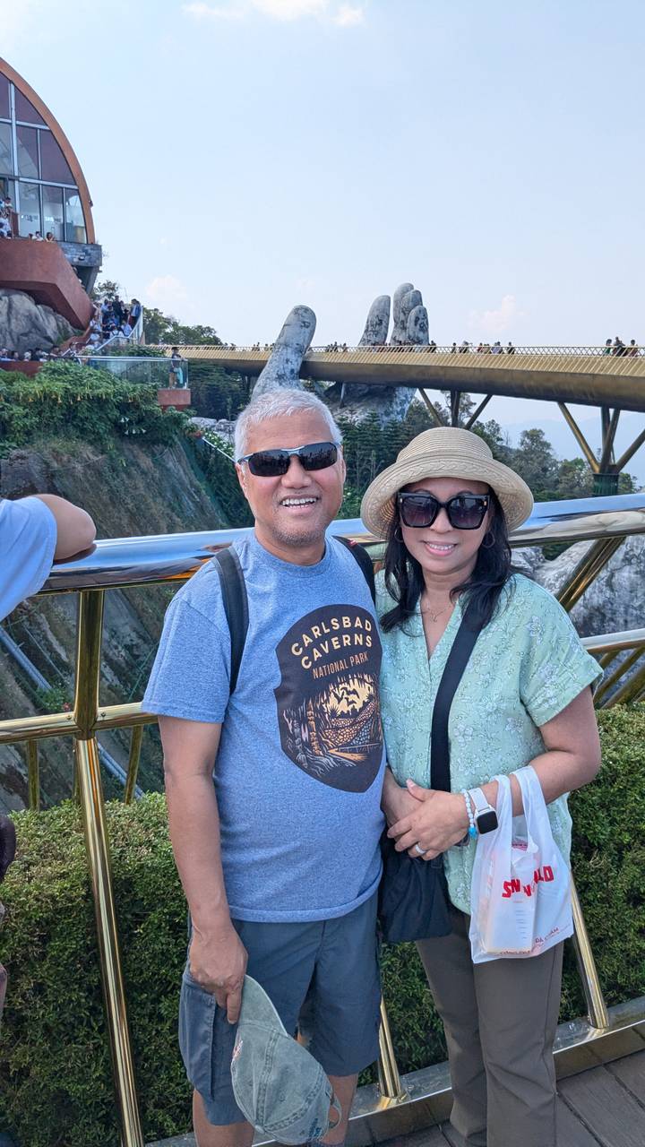 Couple smiling on the Golden Bridge with jungle valley below.