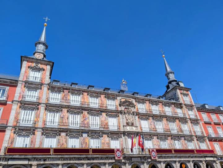 Ornate façade of the Casa de la Panadería on Madrid’s Plaza Mayor glowing against a deep blue sky.