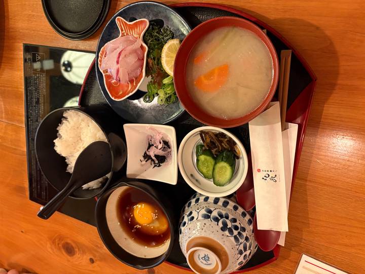 Traditional Japanese meal tray featuring rice, miso soup, sashimi and fresh condiments.