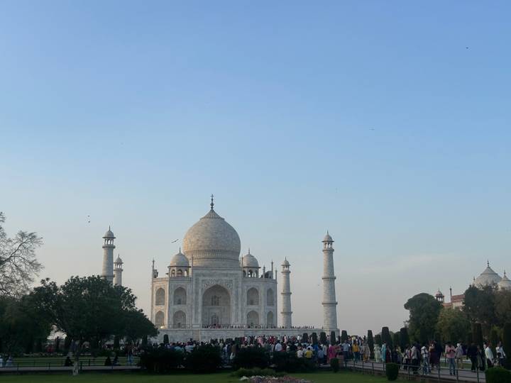 The iconic white marble Taj Mahal framed against a pale blue evening sky.