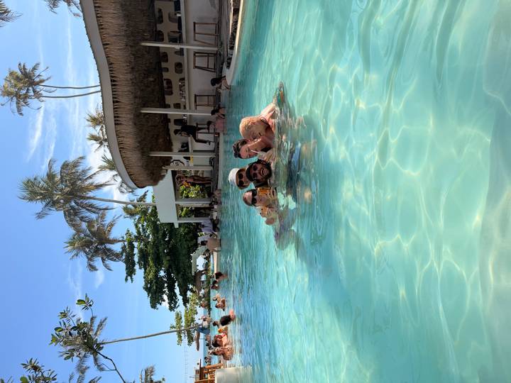 Small group enjoys cocktails while relaxing in a turquoise pool at a beachfront bar.