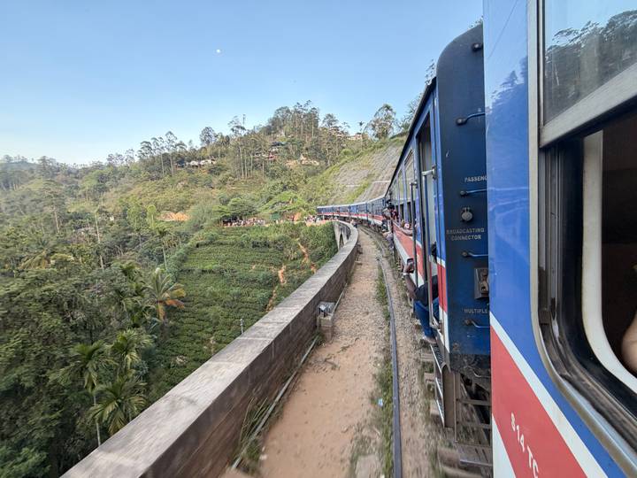 Scenic view from a blue train curving through lush Sri Lankan highlands.