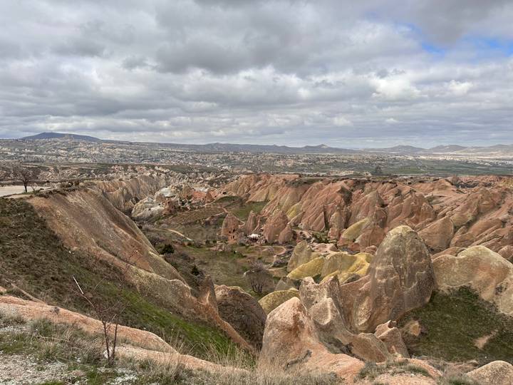 Expansive view over Cappadocia’s multicoloured ridges and valleys under a brooding sky.