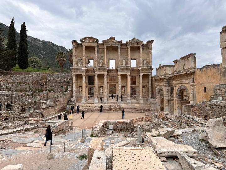 Ruins of the Library of Celsus in Ephesus with scattered visitors exploring the ancient site.