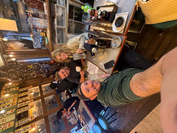 Selfie of three friends enjoying beer at a cozy Japanese izakaya.