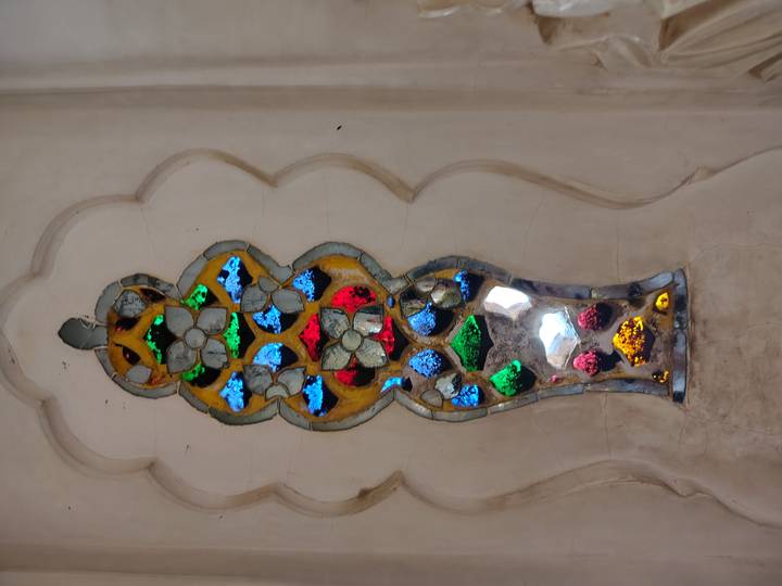 Close-up of ornate multicolored glass inlay set into a white marble wall.