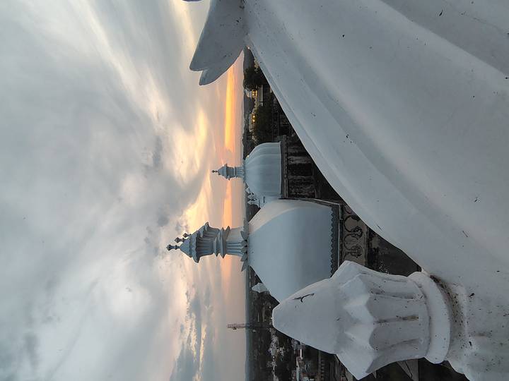 White rooftop domes with decorative finials against a dramatic sunset sky.