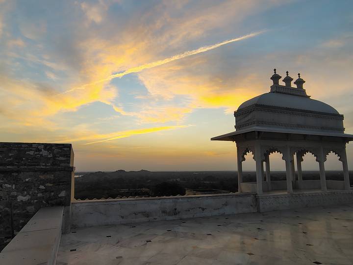 Silhouette of a pavilion dome on a rooftop terrace against pastel dawn clouds.