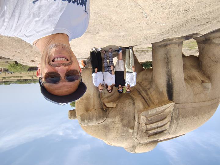 Traveler taking a selfie with friends in front of a large stone elephant sculpture.