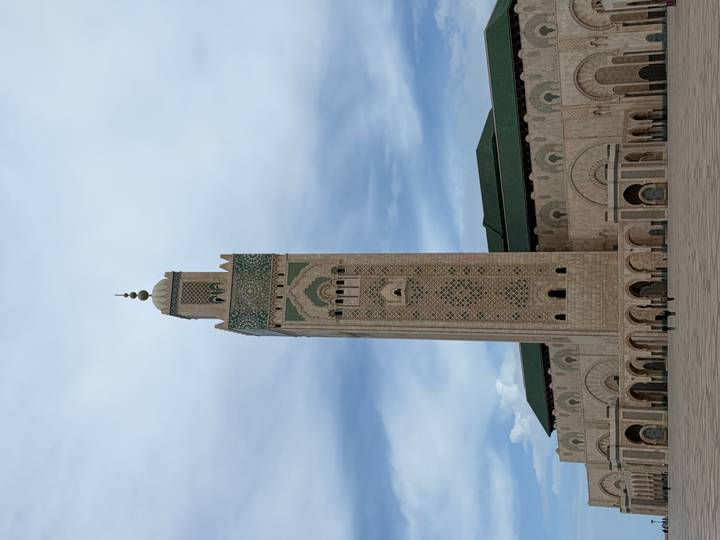 Tall minaret and courtyard of the Hassan II Mosque under a bright sky.